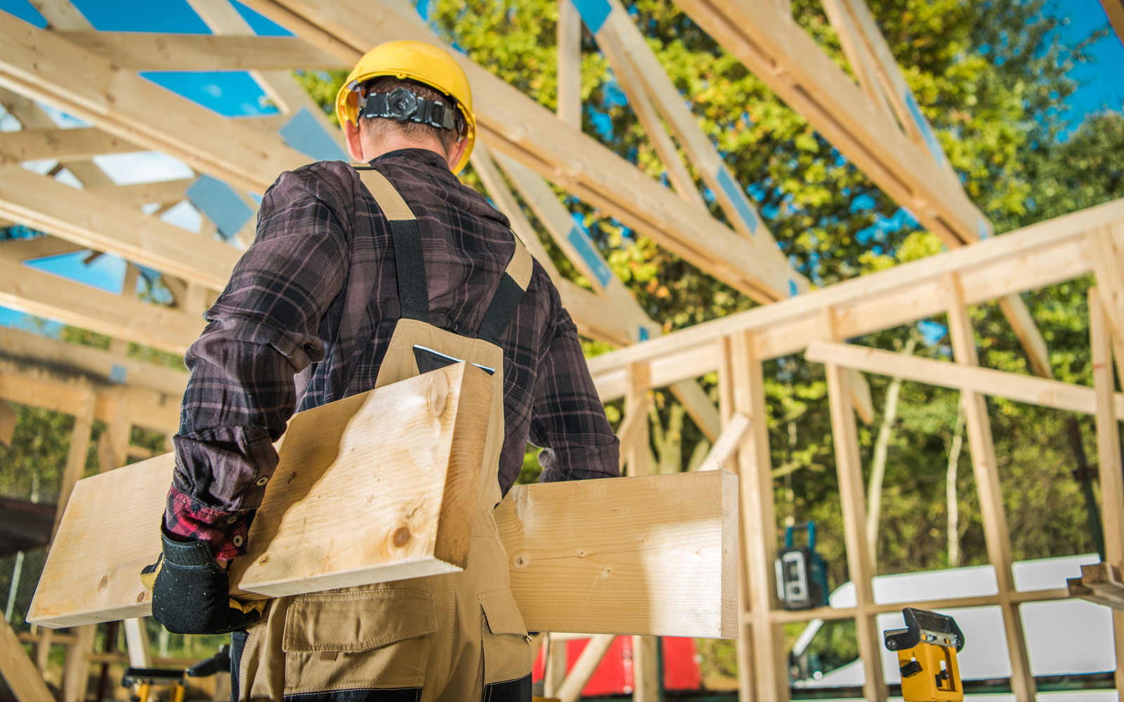 Holzgerüst eines Hauses und ein Bauerbeiter der Holzbretter trägt