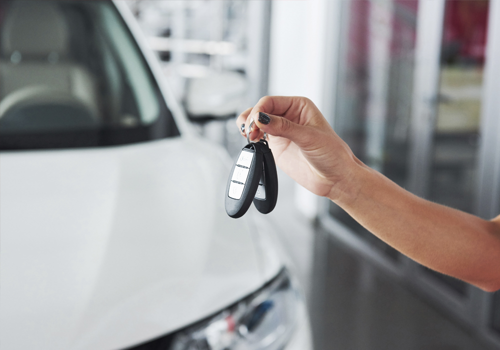 Person hält einen Schlüsselvor seinem Auto hoch