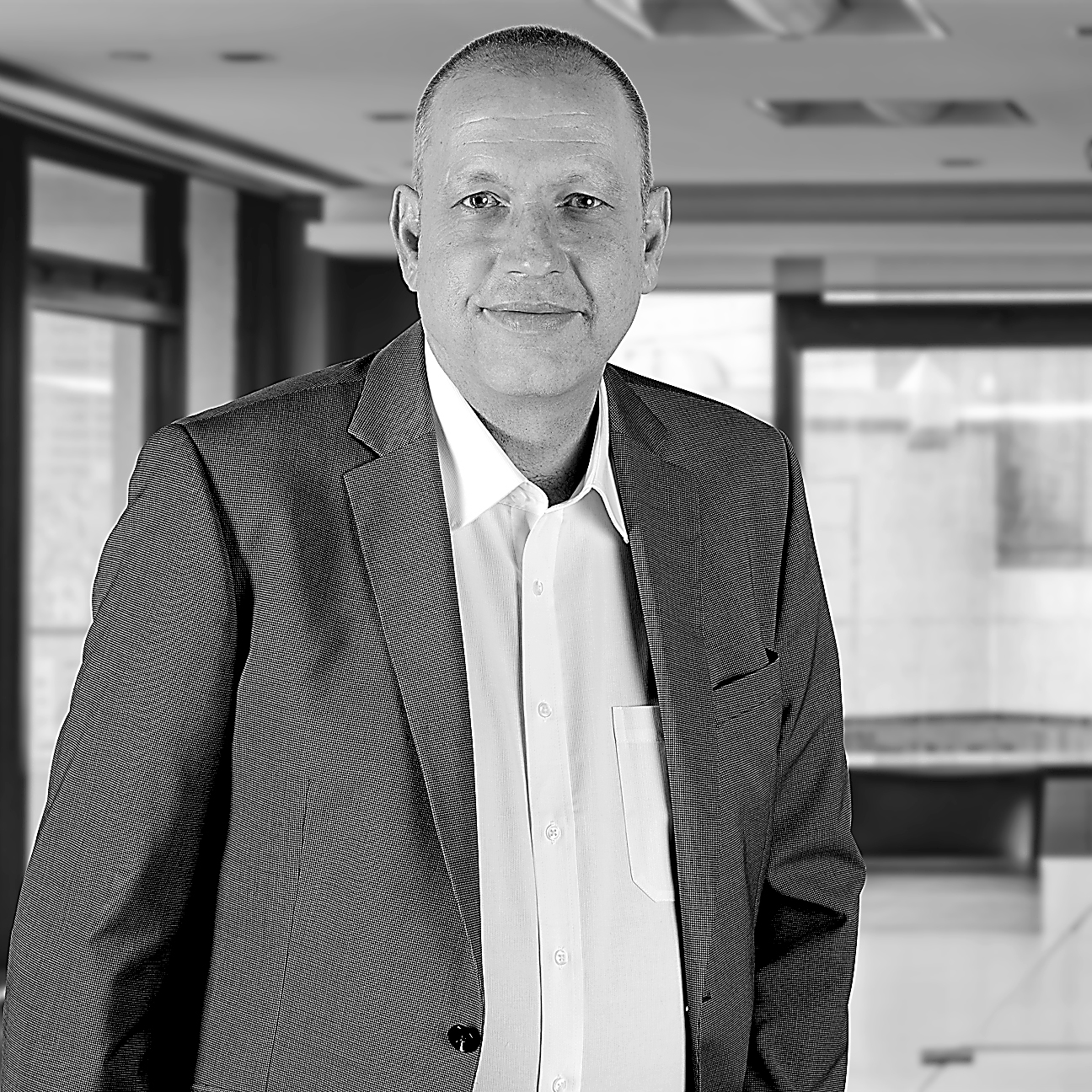 Herr Esslinger von VITARELI Versicherungen steht in einem Büro und lächelt in die Kamera