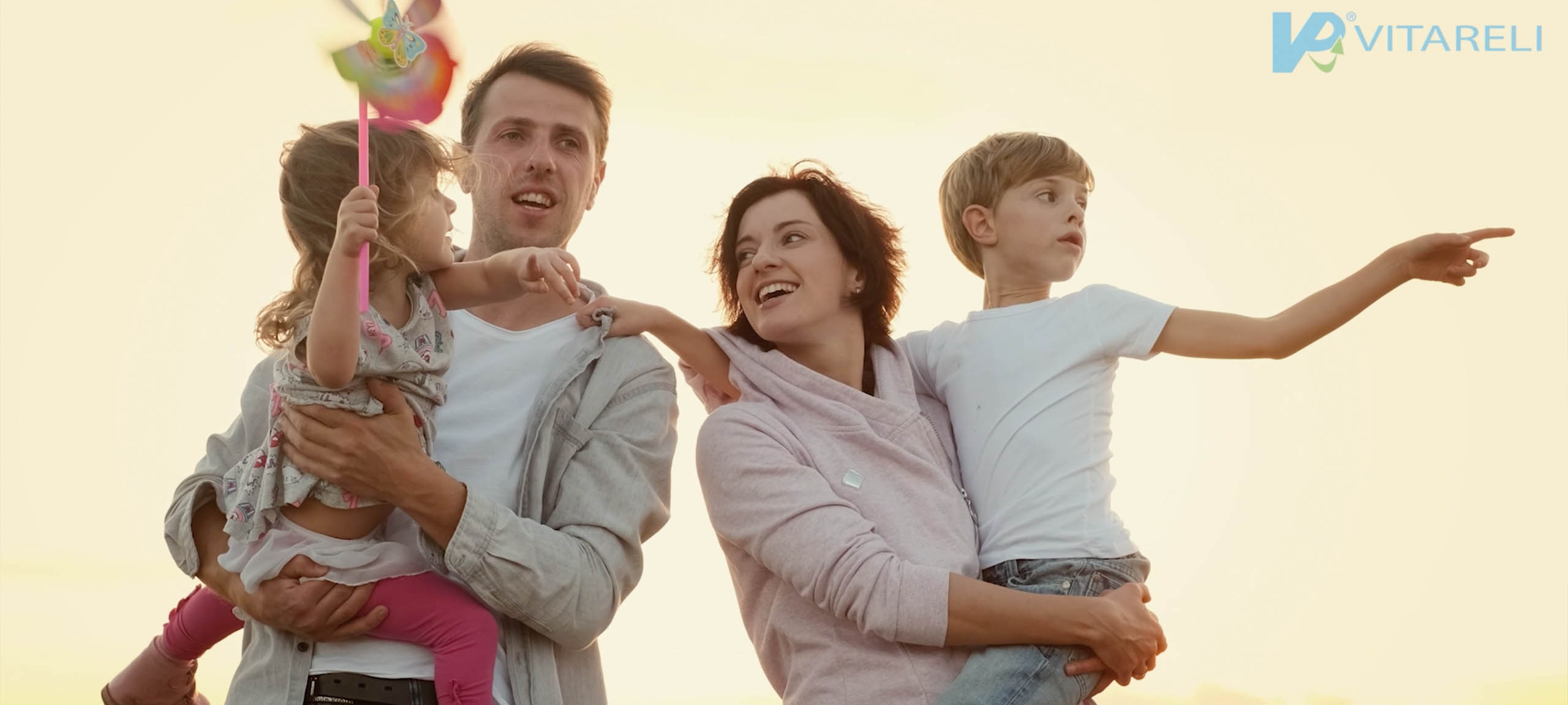 Screenshot von dem VITARELI Versicherungen Imagevideo, man sieht eine Familie mit zwei Kinder, die von den Eltern getragen werden