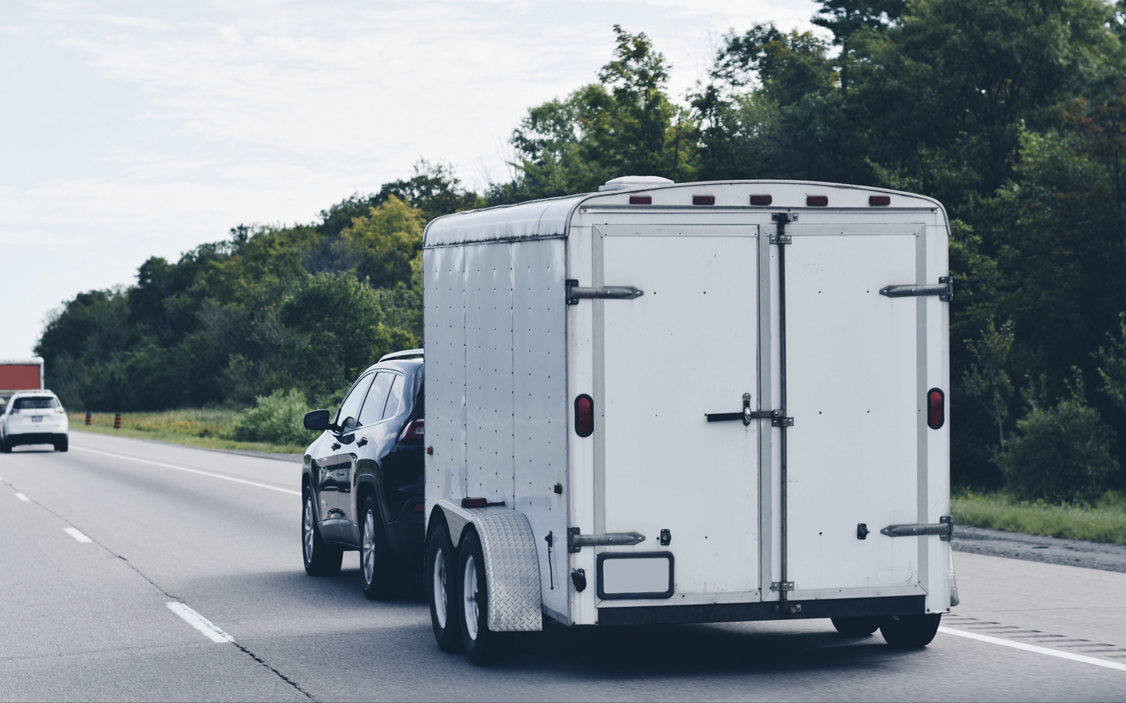 Auto mit einem mittel großen Anhänger von hinten auf der Autobahn